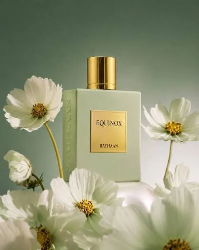 Rayhaan Equinox entre flores blancas, frasco verde claro con tapon dorado